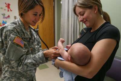Army doctor examines baby held by its mother