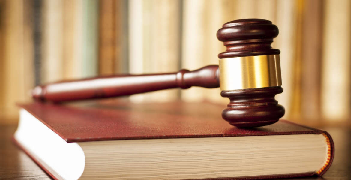 Judges wooden gavel resting on a law book in a courtroom conceptual of judgements, crime, punishment, and justice