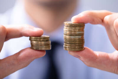 Man Holding Two Coin Stacks To Compare