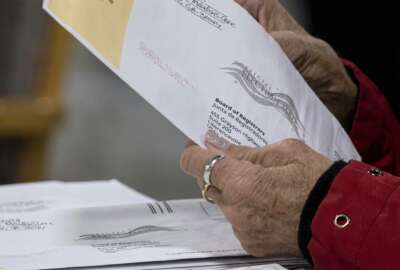 FILE - In this Jan. 6, 2021 file photo, workers at the Gwinnett County Georgia elections headquarters process absentee ballots for Georgia's Senate runoff election in Lawrenceville, Ga.  When voters in Florida and Georgia request mailed ballots next year, they will have to make sure they do one more thing before sending it in: provide proof of identification.  (AP Photo/Ben Gray, File)
